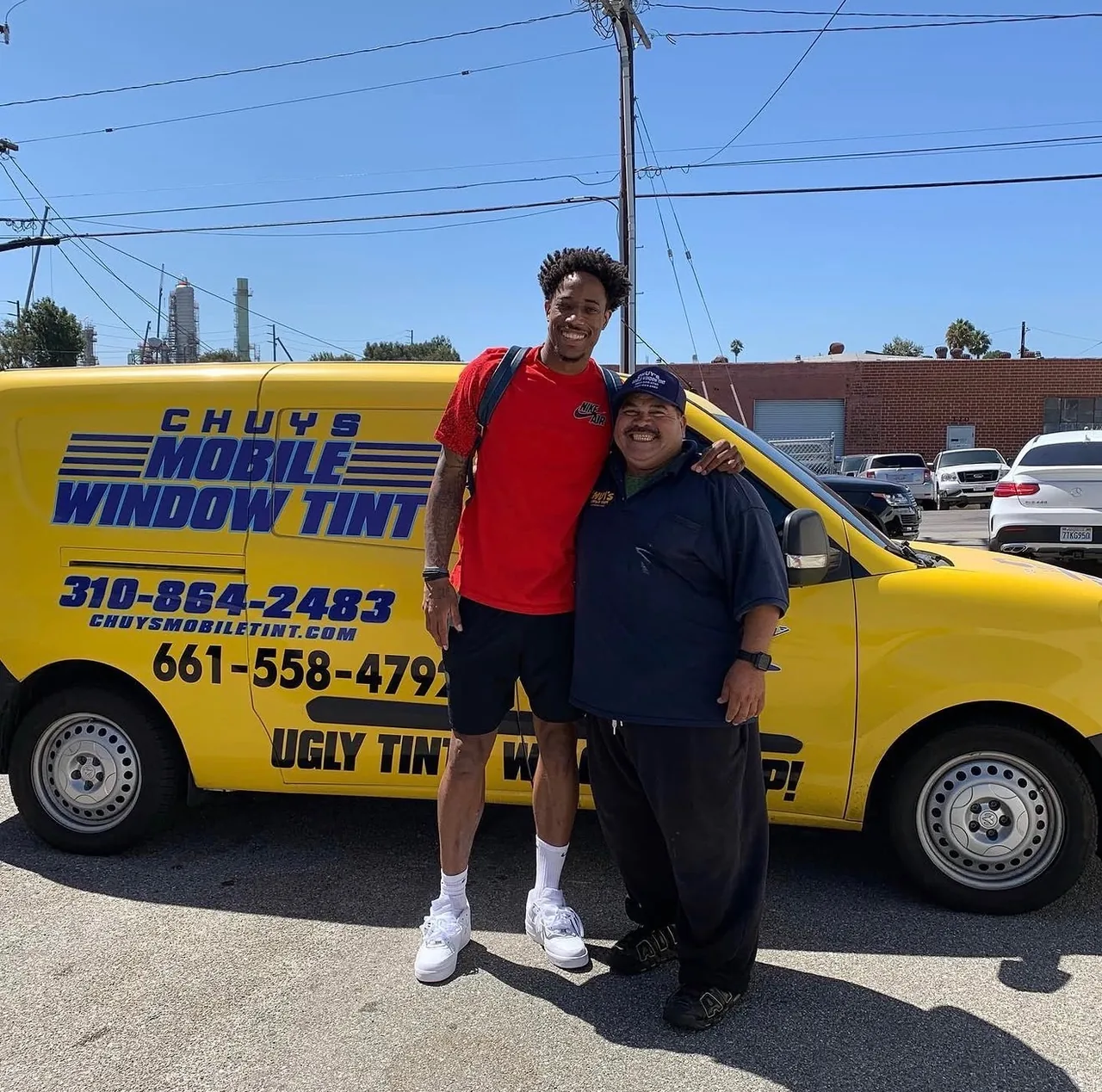 Chuy standing with a happy customer in front of the Chuy's Mobile Window Tint van