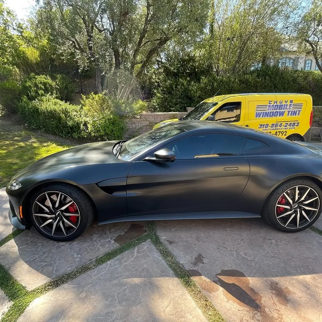 Matte black Aston Martin Vantage tinted on site with the Chuy's mobile service van in the background